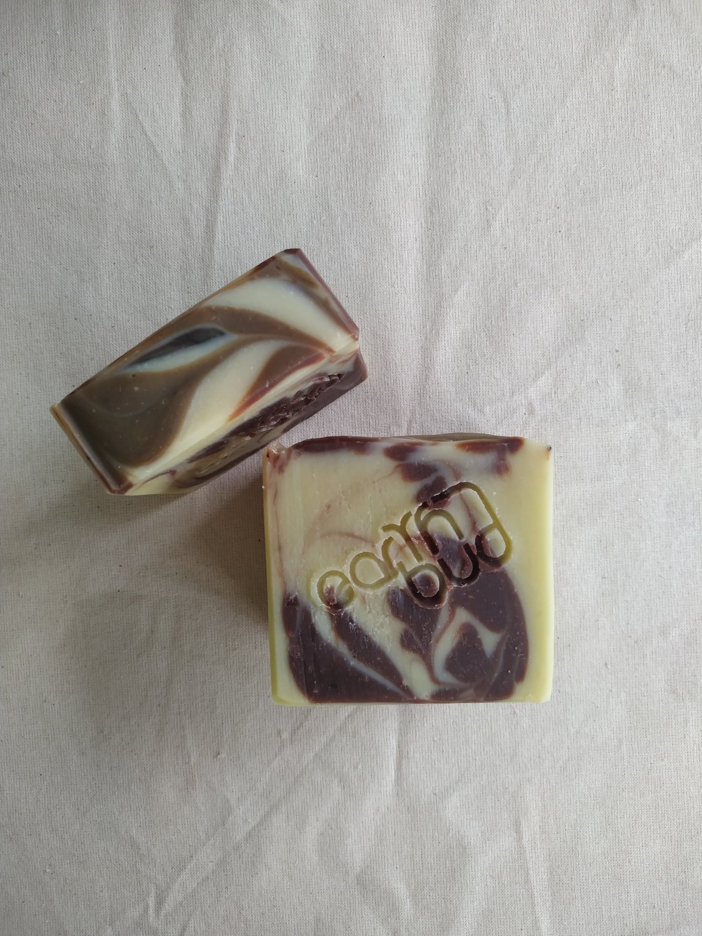 cream coloured soap with cacao brown swirls and stamped with Earth Bud logo